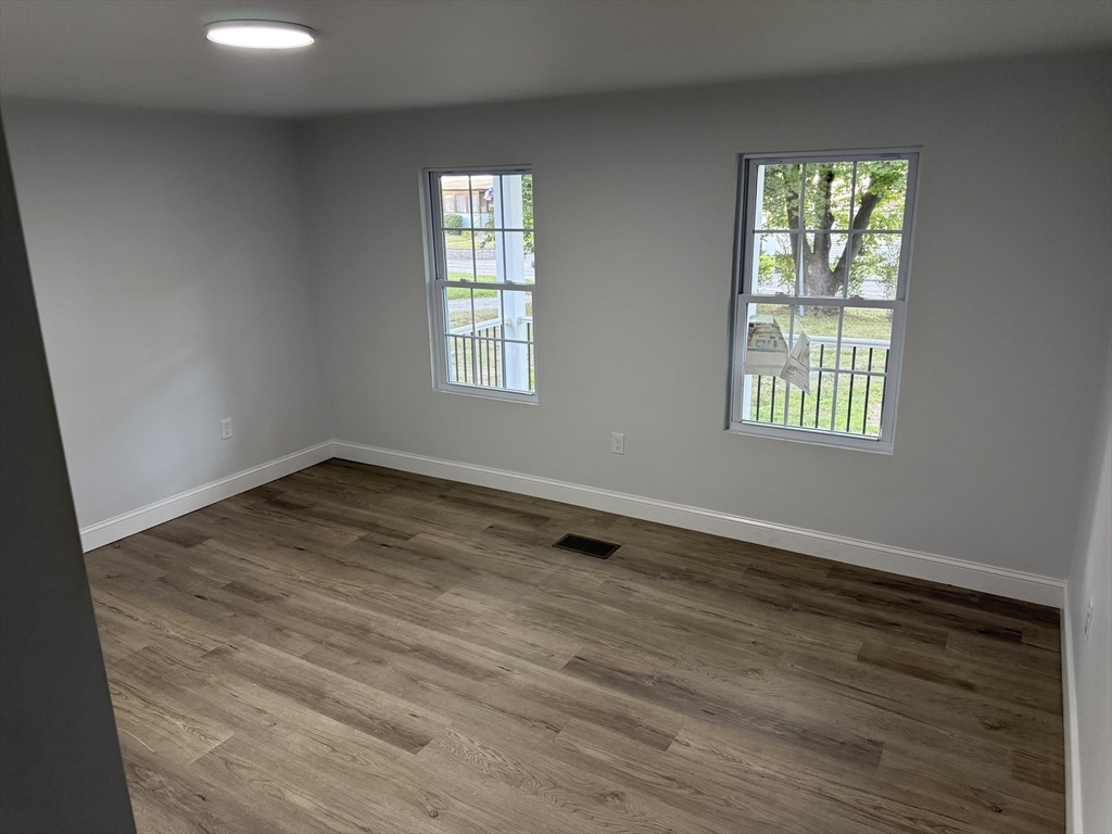 27 Leicester Street, Unit 1 Oxford, MA 01537 - Photo 25 of 26 an empty room with wooden floor and windows
