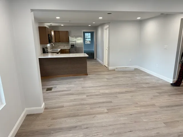 a view of kitchen with kitchen island stainless steel appliances wooden floor and window
