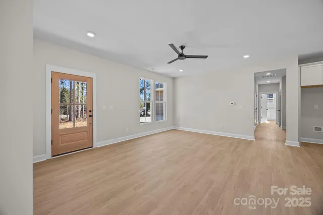 a view of an empty room with a window and wooden floor