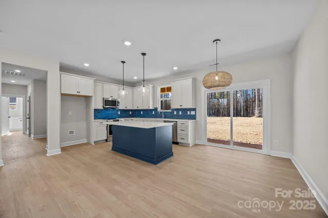 a large kitchen with stainless steel appliances kitchen island a large counter top and a wooden floor