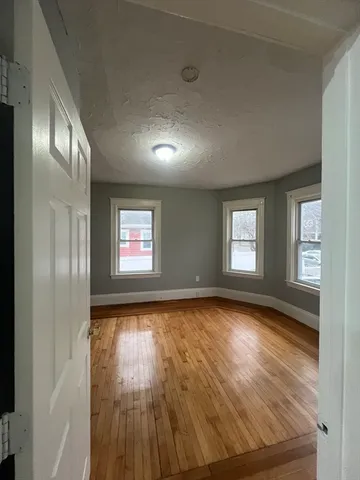 a view of an empty room with wooden floor and a window