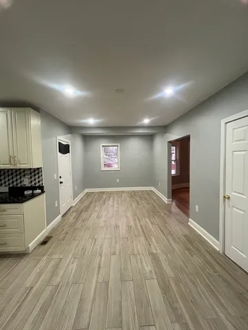 an empty room with wooden floor cabinet and windows