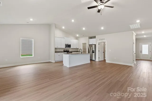 a view of kitchen with stainless steel appliances refrigerator stove and wooden floor