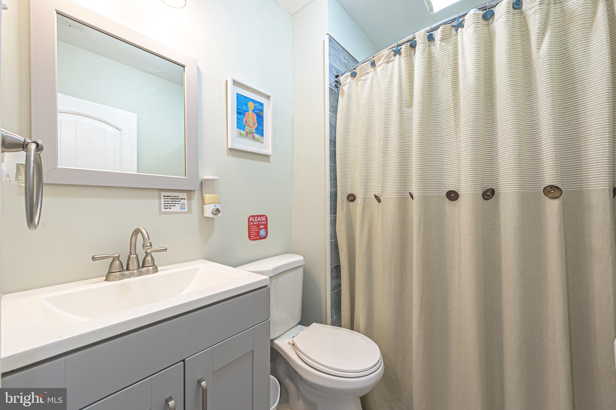229 10th Street North, Unit 2 Brigantine, NJ 08203 - Photo 11 of 24 a bathroom with a sink a toilet and shower curtain