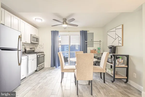a kitchen with stainless steel appliances a dining table chairs refrigerator and sink