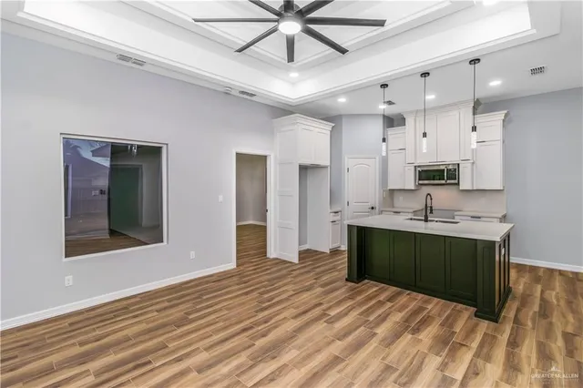 a kitchen with stainless steel appliances kitchen island granite countertop a sink cabinets and wooden floor