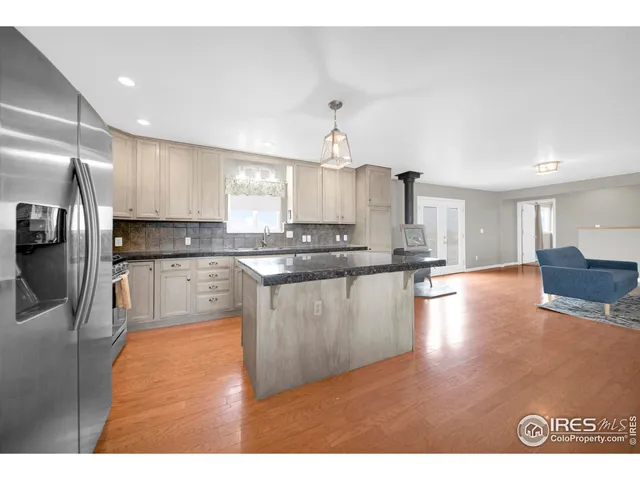 a kitchen with stainless steel appliances granite countertop a stove top oven a sink a dining table and chairs with wooden floor