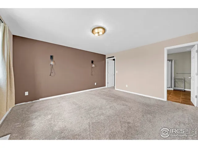 a view of an empty room with a window and a kitchen