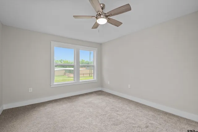 an empty room with a window and a fan
