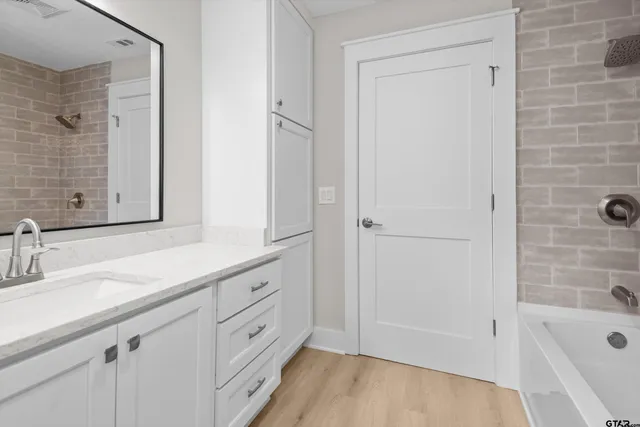 a bathroom with a double vanity sink a mirror and a bathtub