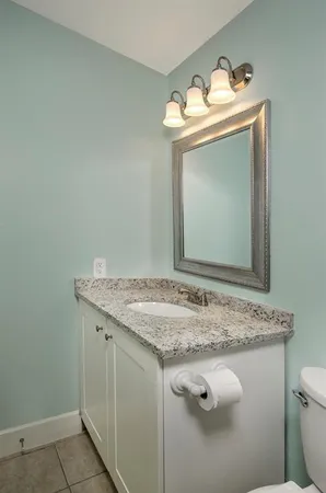 a bathroom with a granite countertop sink mirror vanity and toilet