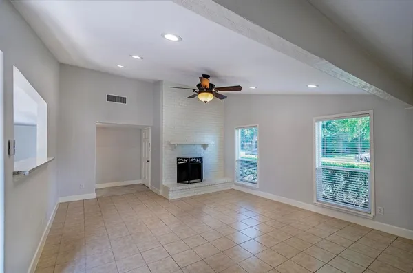 an empty room with windows and fireplace