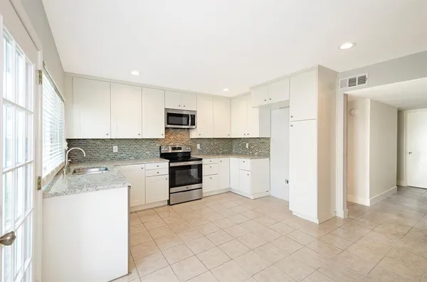 a kitchen with granite countertop a refrigerator and a stove top oven