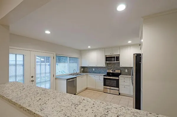 a kitchen with a refrigerator a stove top oven and white cabinets