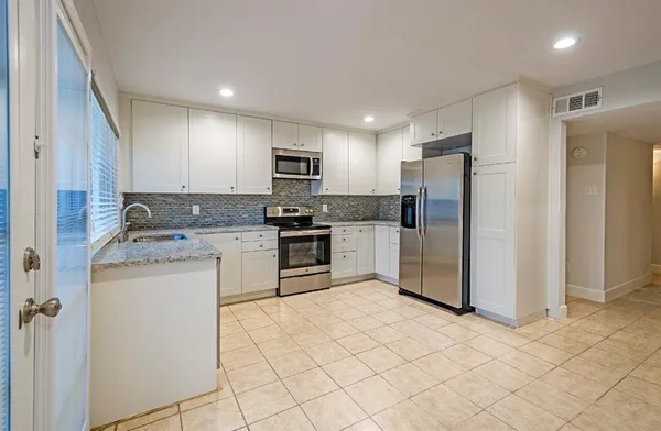 a kitchen with granite countertop white cabinets and white appliances