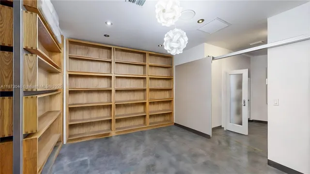 an empty room with a chandelier fan and windows