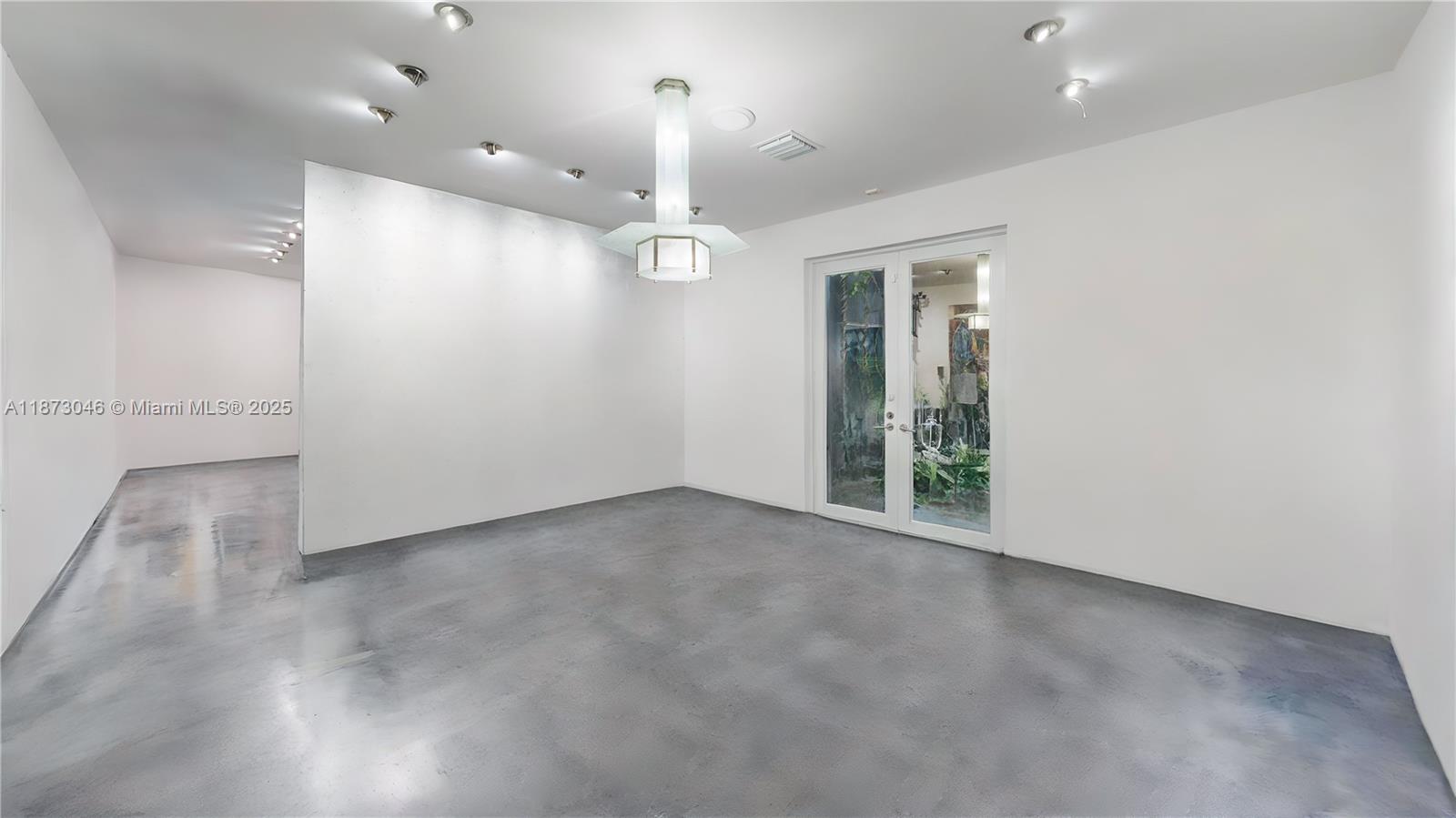 2101 Tigertail Avenue Miami, FL 33133 - Photo 46 of 92 an empty room with a chandelier fan and windows