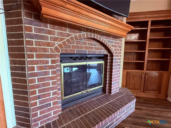 a view of an empty room with wooden floor and a fireplace
