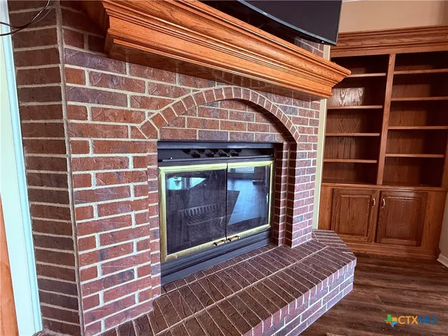 a view of an empty room with wooden floor and a fireplace