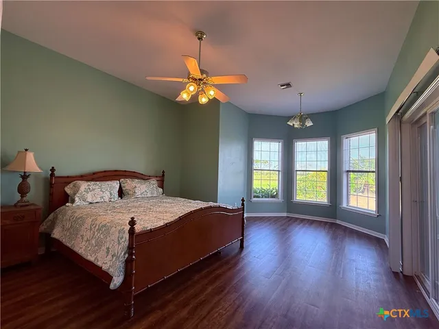 a bedroom with a large bed chandelier and a large window