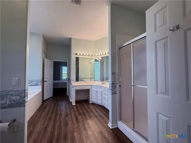 a view of a bathroom with tub shower window and wooden floor