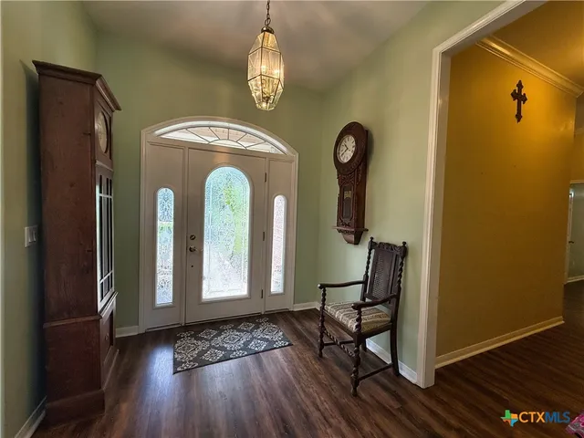 a view of a hallway with wooden floor table and chairs