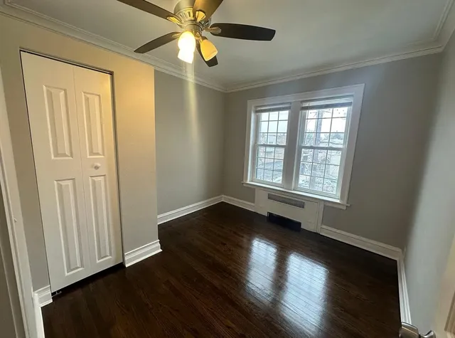 an empty room with wooden floor chandelier fan and windows