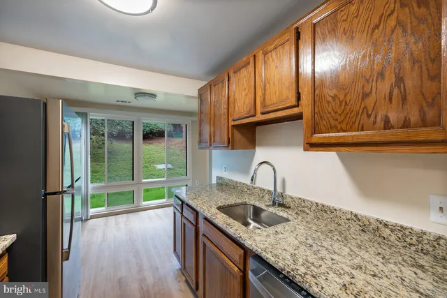 a kitchen with granite countertop a sink a stove and a wooden floors