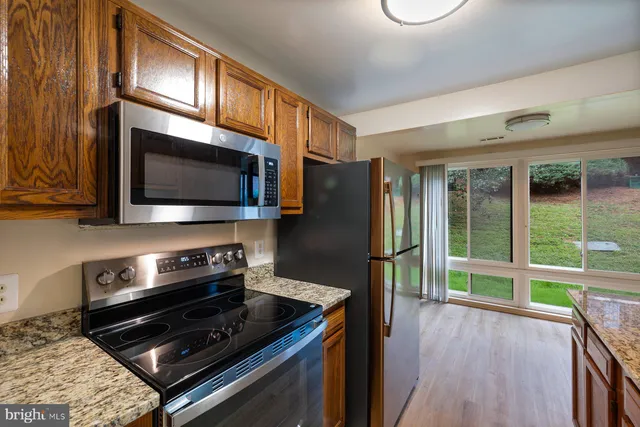a kitchen with stainless steel appliances a stove a microwave and a hard wood floor