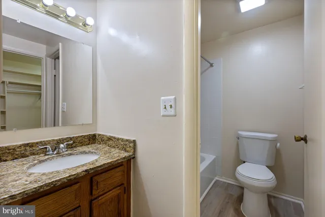 a bathroom with a granite countertop sink toilet and a mirror