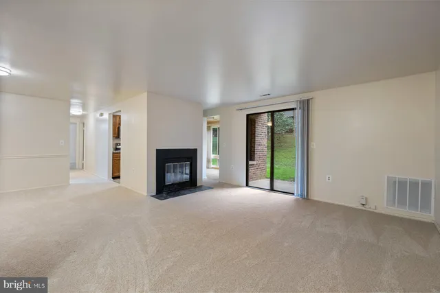 a view of an empty room with a fireplace and a window