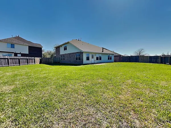 a view of a house with a yard and a large tree