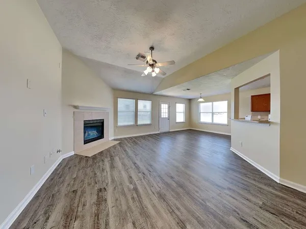 a view of an empty room with window and wooden floor