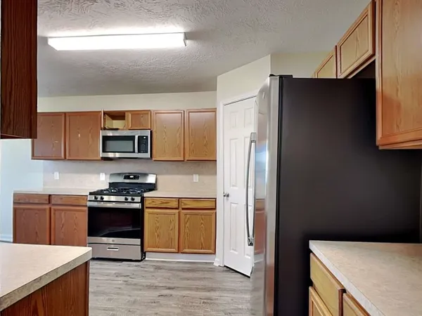 a kitchen with stainless steel appliances a stove a refrigerator a sink a counter space and cabinets