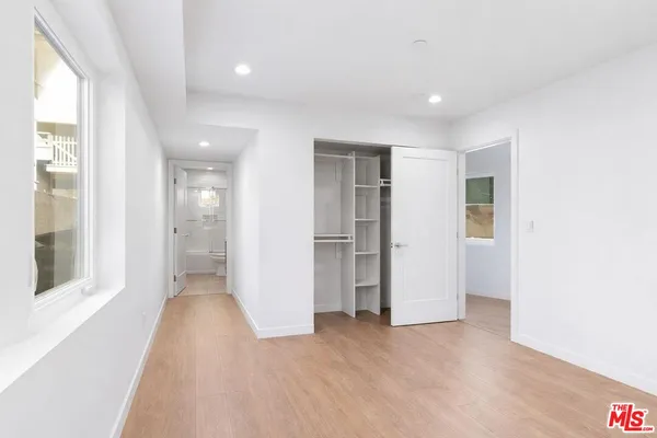 a view of a hallway with wooden floor and a bathroom