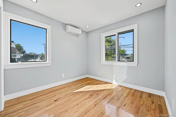 a view of an empty room with window and wooden floor
