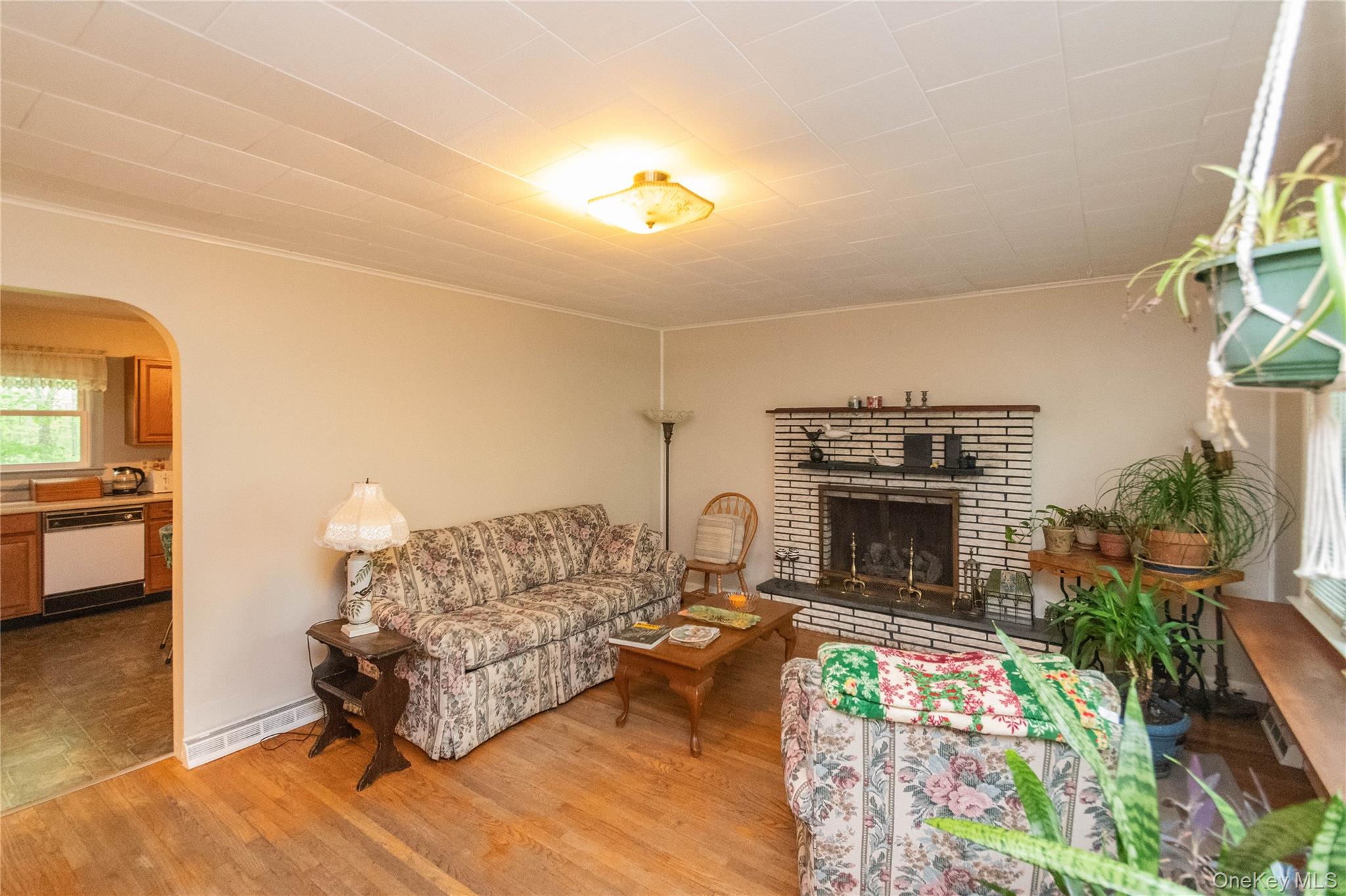 543 Dosen Road Middletown, NY 10940 - Photo 8 of 25 Living area featuring wood-finish flooring, a white brick fireplace with a black hearth, and an arched doorway