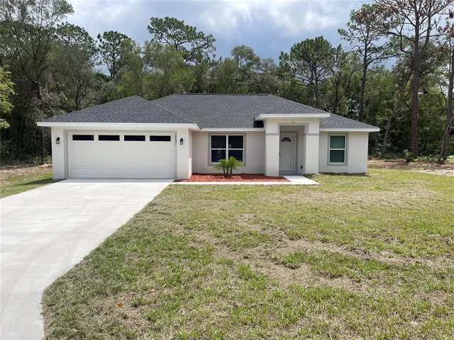 a front view of house with yard and trees in the background