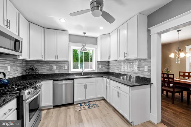 a kitchen with stainless steel appliances granite countertop white cabinets granite counter tops and a hard wood floors