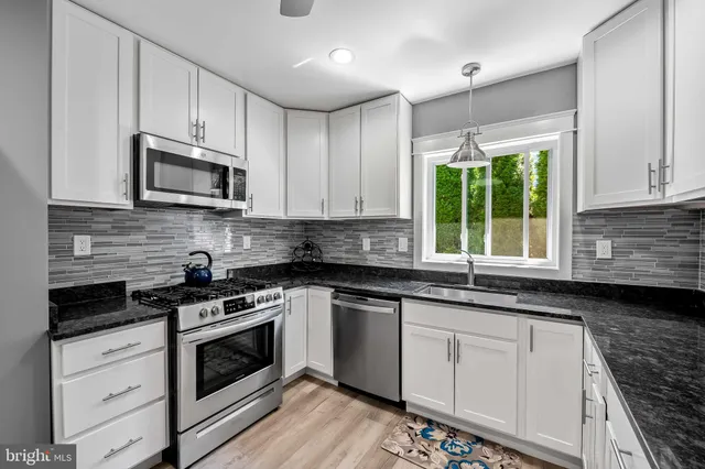 a kitchen with granite countertop a sink a stove a microwave and cabinets