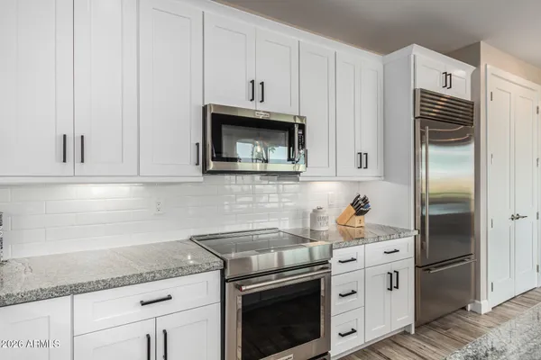 a kitchen with stainless steel appliances granite countertop a sink a stove a refrigerator and cabinets