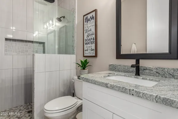 a bathroom with a granite countertop sink a toilet and shower