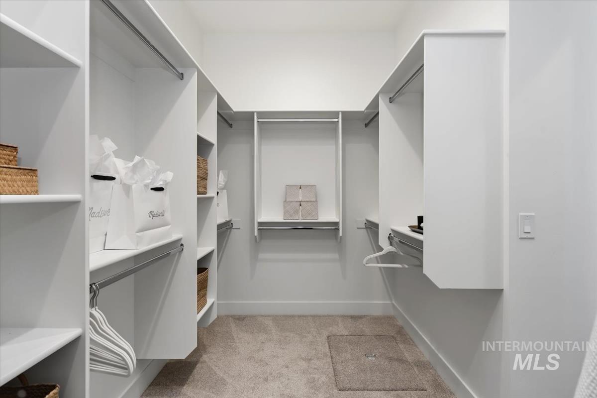 7615 Brown Way Eagle, ID 83714 - Photo 32 of 43 Walk-in closet featuring built-in white shelving, multiple hanging rods, and neutral carpet flooring