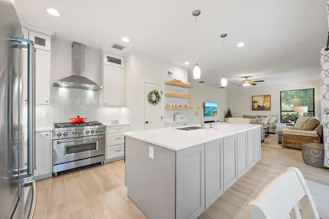 a living room with stainless steel appliances furniture a rug and a large window