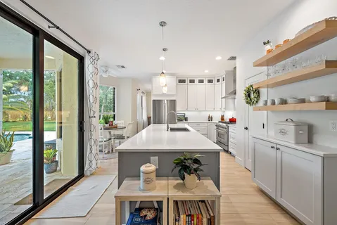 a large white kitchen with a large window and stainless steel appliances