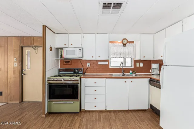 a kitchen with granite countertop a refrigerator stove a sink and dishwasher with wooden floor