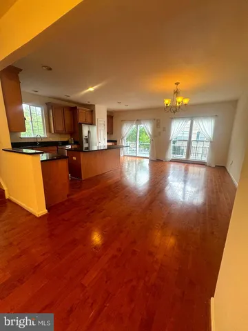 a view of a living room with kitchen island granite countertop wooden floor and a large window