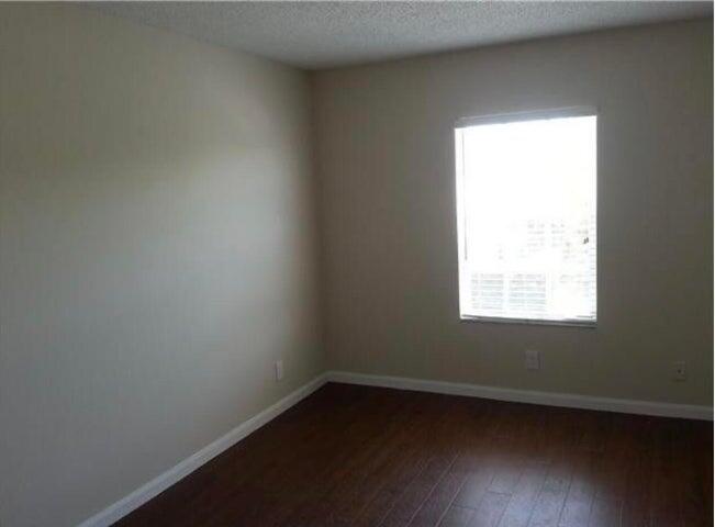 5267 Pine Meadows Road Lake Worth, FL 33463 - Photo 11 of 17 an empty room with wooden floor and windows
