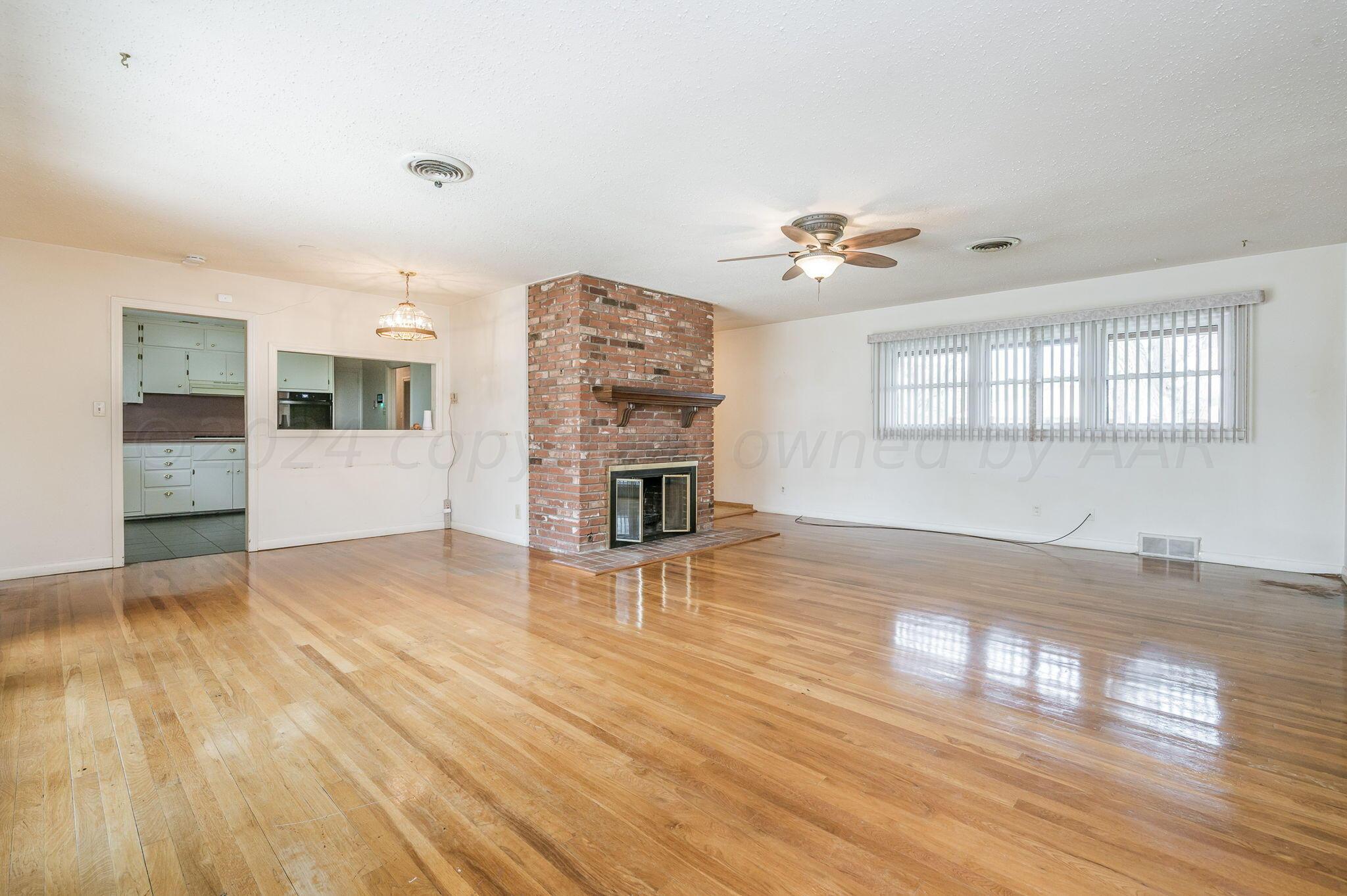 3415 Paramount Boulevard Amarillo, TX 79109 - Photo 12 of 44 an empty room with wooden floor and fireplace
