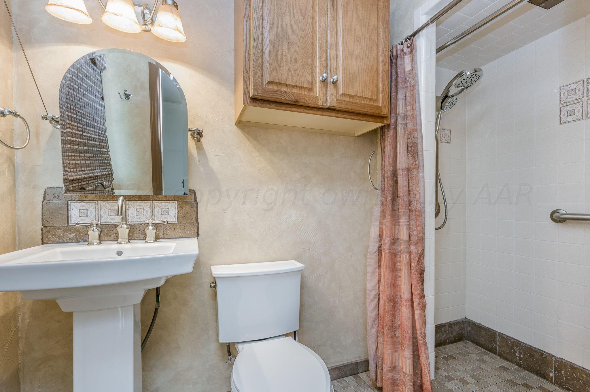 3415 Paramount Boulevard Amarillo, TX 79109 - Photo 22 of 44 a bathroom with a sink a toilet and shower curtain
